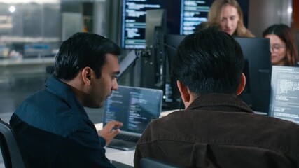 Two Software Developer, Programmer discussing, explaining to colleague working on code, application software development project using desktop computer, work together in co-working office space.