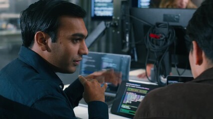 Two Software Developer, Programmer discussing, explaining to colleague working on code, application software development project using desktop computer, work together in co-working office space.