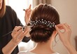 © yuan - Hairstylist Creating Elegant Updo with Pearl Accents.