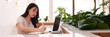 © snowing12 - Asian young adult woman freelancer digital nomad working online cafe studying writing notes laptop modern workspace bright natural light productivity focus