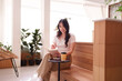 © snowing12 - Asian woman freelancing cafe writing notes enjoying coffee relaxed creative workspace remote work setting bright environment productivity focus