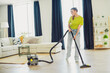 © deagreez - Cheerful woman happily vacuuming a bright, modern living room with stylish interior decor showcasing a balanced home life