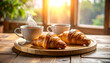 © Bill - Breakfast of tea and buttery croissants on a round wooden tray. AI
