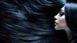 © Khan - A woman with long, dark hair, wearing a black top, standing in front of a black background.