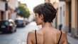 © Roberto - portrait of a brunette woman model with short hair and nude shoulders in the street, back view, model photography