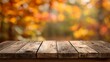 © Rifqi - Rustic wooden table surface with autumn foliage background out of focus in warm light, concept for seasonal product display, fall promotions and harvest festival ads