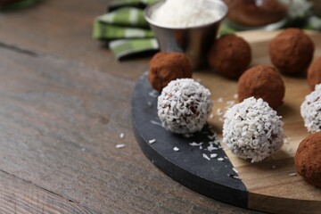 Wall Mural - delicious homemade candies with cocoa powder and coconut flakes on wooden table, closeup. space for 