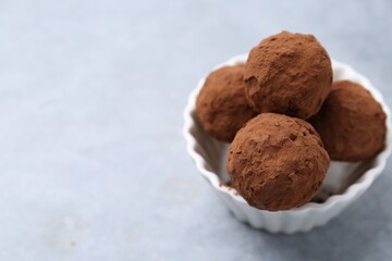 Wall Mural - delicious homemade candies powdered with cocoa in bowl on light table, closeup. space for text