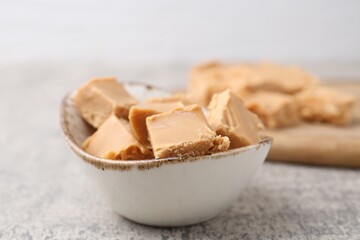 Wall Mural - homemade caramel candies in bowl on light grey table, closeup