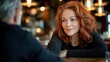 © OM - Restaurant conversation captured with woman in burgundy sweater, wavy hair, gentle expression, leaning forward attentively, warm restaurant ambiance, authentic interaction