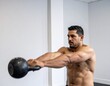 © Parkpoom - Kettlebell Workout: A muscular athlete grips a heavy kettlebell, embodying strength and focus as he prepares for a dynamic exercise in a fitness studio.