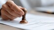 © MuhammadHajiji - Hand Applying Wooden Stamp on Official Document for Verification Process