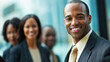 © Keo - A smiling African American businessman in a suit with a group of people in the background.