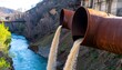 © iya - Rusty pipes discharge contaminated water into a river