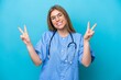 © luismolinero - Young surgeon doctor woman isolated on blue background showing victory sign with both hands
