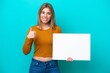 © luismolinero - Young caucasian woman isolated on blue background holding an empty placard with thumb up