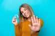 © luismolinero - Young caucasian woman holding invisible braces isolated on blue background saluting with hand with happy expression