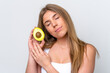 © luismolinero - Young caucasian woman isolated on white background holding an avocado. Close up portrait