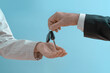 © TSViPhoto - Hand of man in a formal suit handing over car keys to a woman's hand. Concept of selling or renting a car