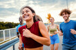 © Zoran Zeremski - Smiling group of people running together on outdoor road.