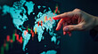 © Ruhel - Hand pointing at a world map with stock market charts and data overlays indicating global financial activity