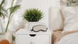 © AkuAku - Comfortable sleeping area featuring a mask, earplugs, and a plant on a white bedside table