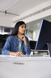 © fizkes - Serious young Indian professional woman in casual working on creative startup project at pc monitor in office, using business application, online modern technology for job task. Vertical shot