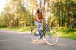© maxbelchenko - Young woman riding a bicycle on a path in a dense sunny forest. Happy woman enjoying nature and cycling at sunset. Weekend concept. Active lifestyle.