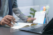 © gothong_1984 - A table for tracking progress of work each quarter, start and end weeks, percentage of completion of activities, marketing trends, and a graph showing annual profits. Businessman working in an office.