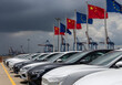 © Lacobus - A row of cars with chinese and european union flags waving in the background at a shipping port area