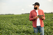 © Тетяна Шустик - Smart farming technology in action — a modern male farmer in a soybean field checking crop data on a tablet. Concept of precision agriculture, digital innovation, and efficient farm management.