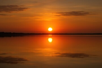 Wall Mural - a symphony of orange hues reflecting on still waters