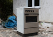 © Luka - Old used gray stove next to a trash pile. Electronic waste. old kitchen appliance. Destroying the environment. Unnecessary waste