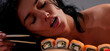 © Volodymyr - Sushi closeup in sexy woman mouth. Sexy woman eating sushi with chopsticks. Model eat sashimi. Sensual bite of sushi. Female tasting nigiri. Lunch at Japanese restaurant. Desire for delicious sushi.