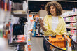 © anatoliycherkas - Woman Choosing Toothpaste in Supermarket While Grocery Shopping