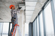 © Serhii - Construction worker installing ventilation system in modern building