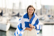 © JackF - Young woman in summer dress wrapped in Greek flag on sea port with yachts