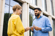 © sofiko14 - Two people exchanging money outdoors near a building. The man is holding cash, the woman is receiving it.