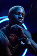 © TrueFrame Collective - Vertical high angle medium studio portrait of modern young Black man wearing casual outfit with paint on his face posing on camera moving his hands
