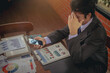 © Panumas - Businessman using smartphone checking business result and seriously by stock exchange down. Selected focus.