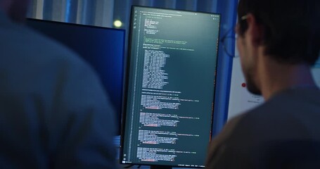 Closeup team adult male engineer collaborate on robotic hand project use AI code solutions machine learn at tech workspace night. Artificial intelligence interface collaboration prototype development.