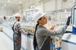 © Serhii - Female factory worker operating machinery with male colleague in background