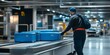 © Angelo - Airport worker managing blue luggage on a conveyor belt system for transport
