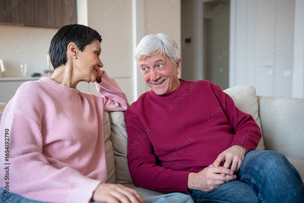 Glad happy senior husband engaging in conversation with wife paying attention on sofa. Companionship after decades, domestic happiness, retired love, shared memories over years, happy married life