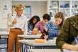 © Rido - Female teacher observes students during exam at high school