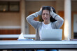 © Austockphoto - Young Asian university student studying on laptop outdoors stressed