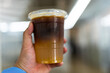 © Dontree - Ice yuzu black coffee in plastic cup on hand.