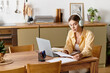 © LIGHTFIELD STUDIOS - A young beautiful woman engages in her studies at a warm and inviting home workspace.