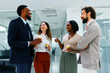 © djile - Multi-ethnic business people laughing and talking during coffee break in modern office hallway