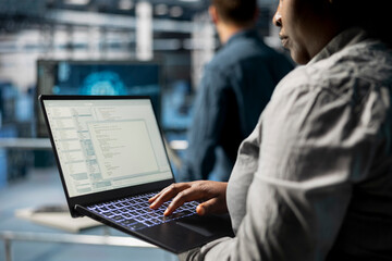 close up of server room coworkers troubleshooting backend operations using software on laptop. team 